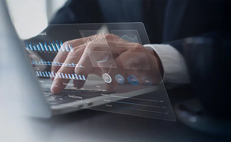 A business man typing on his laptop computer, screen overlayed to show charts and graphs.