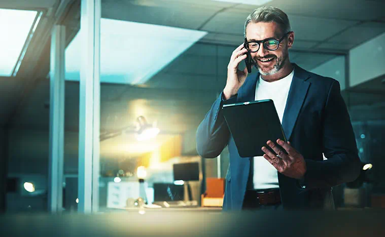 A business man looks at his tablet while on the phone.