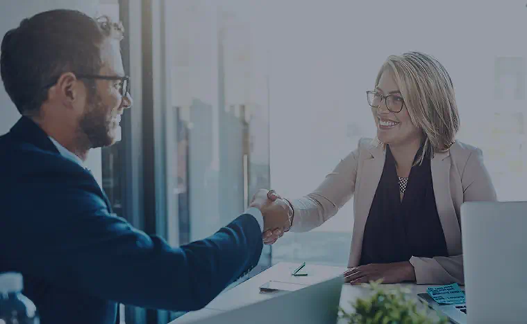 Leading Edge Service Two business people shaking hands in an office.